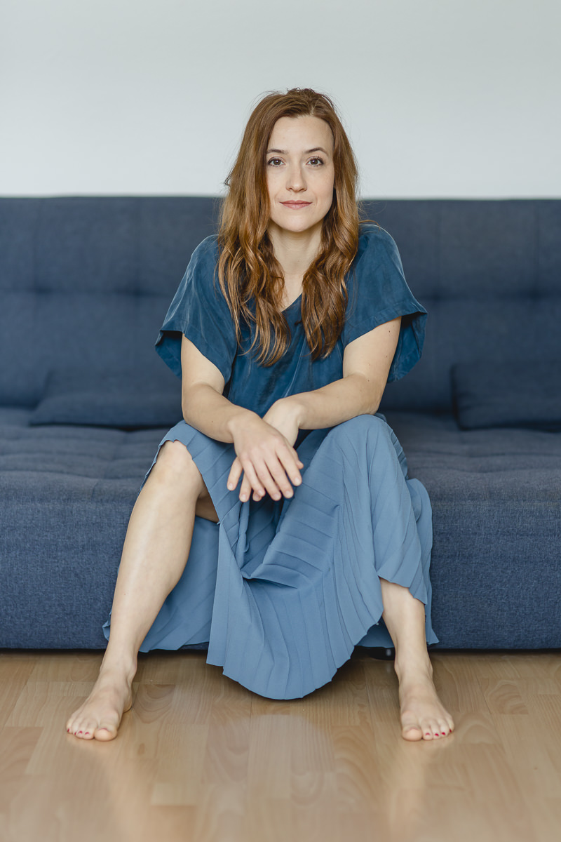 Portraitfoto einer Schauspielerin in ausdrucksstarker Pose, sitzend auf einem blauen Sofa | Foto: Hanna Witte