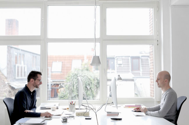 Portraitfoto von 2 Agenturinhabern am Schreibtisch