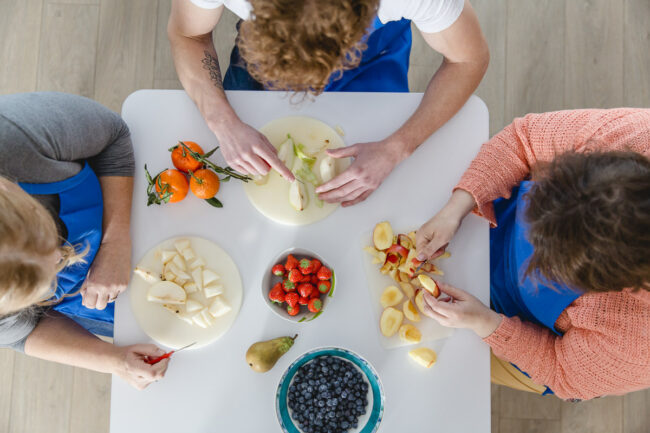Bewohner einer psychiatrischen Einrichtung der Regenbogen Wohnen gGmbH schneiden Obst an einem Tisch | Foto: Hanna Witte