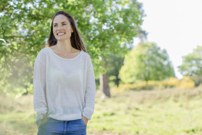 Helles Portraitfoto einer lachenden Yoga Lehrerin in der Natur