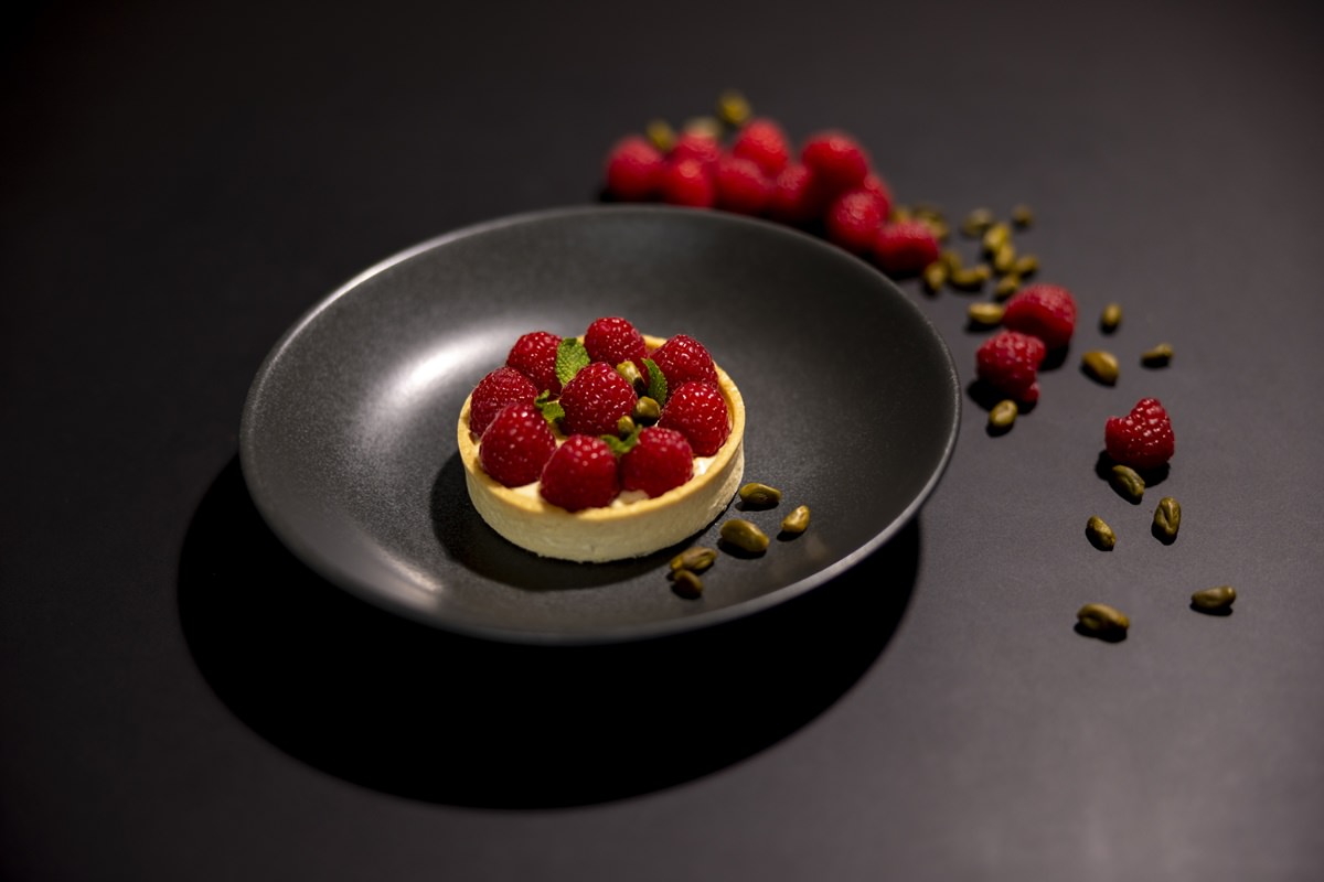 Food Foto eines Dessert-Törtchens mit Heidelbeeren, das auf einem schwarzen Teller angerichtet wurde | Foto: Hanna Witte