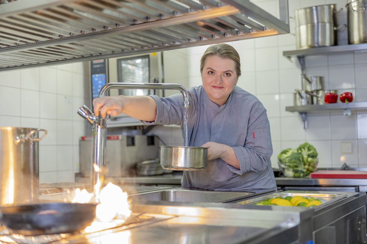 eine Köchin füllt in der Küche des Restaurant Stappen Wasser in einen Topf | Foto: Hanna Witte