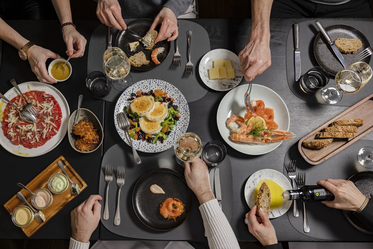 Blick von oben auf einen gedeckten Tisch mit Gästen, die verschiedene Vorspeisen, Dips und Brot im Restaurant Stappen genießen | Foto: Hanna Witte