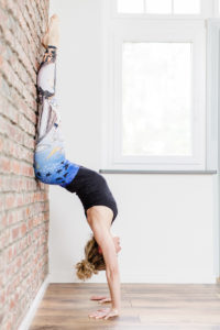 Foto von Yogalehrerin Alexandra Harfield, die eine Yoga Übung an der Wand macht