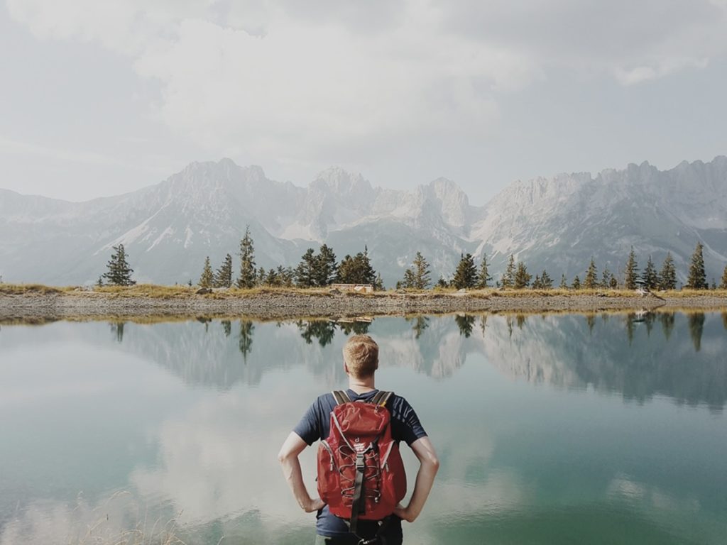 Foto von einem Mann vor wunderschöner Naturkulisse mit einem See, Bäumen und Bergen