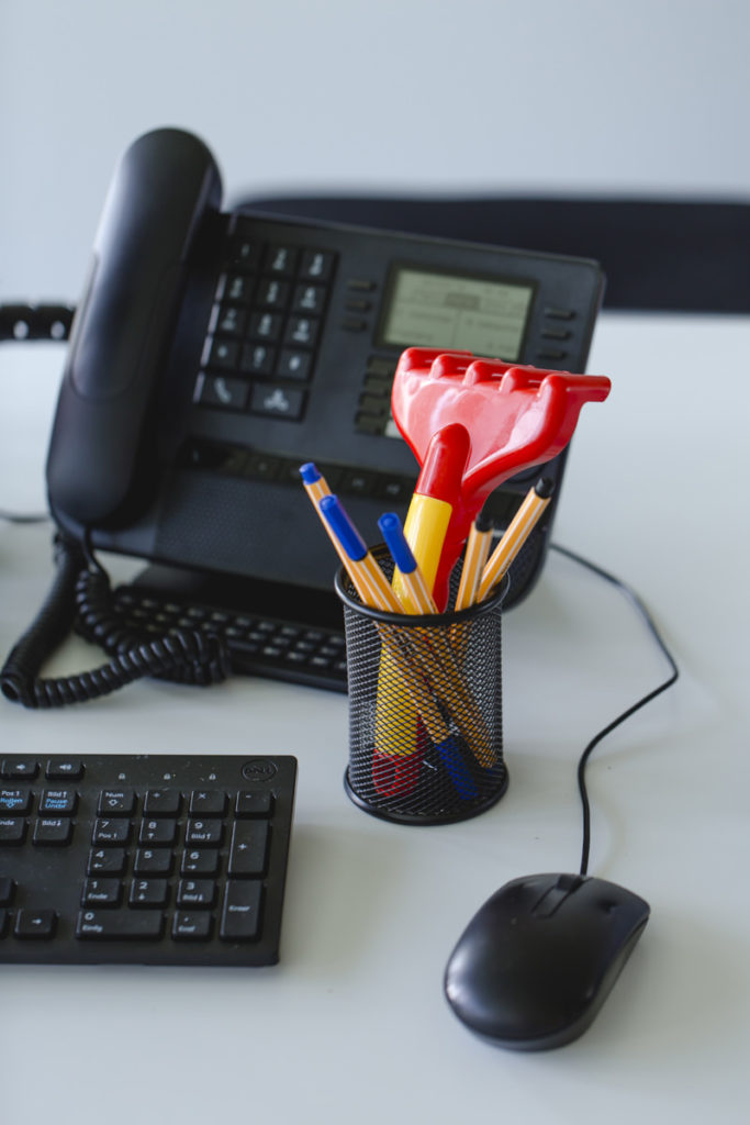 Nahaufnahme Schreibtisch mit Stiften, Telefon, Tastatur und Computer-Maus