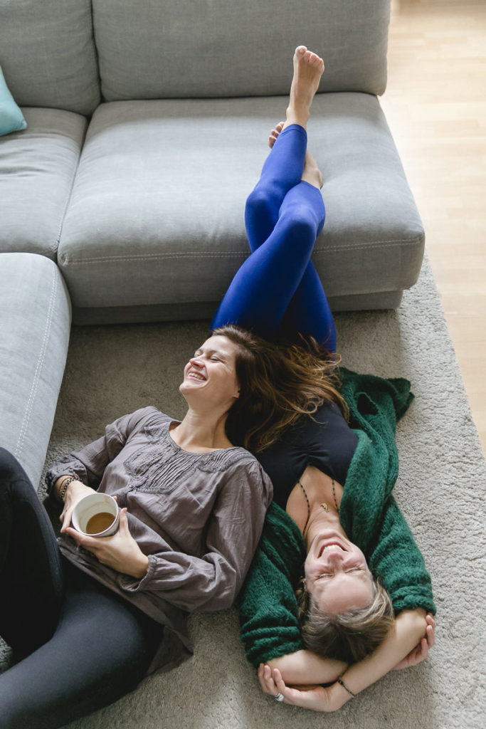 entspanntes Portraitbild der Yoga Lehrerinnen Steffi Grube und Daniela Kourtidis, die auf dem Boden liegen