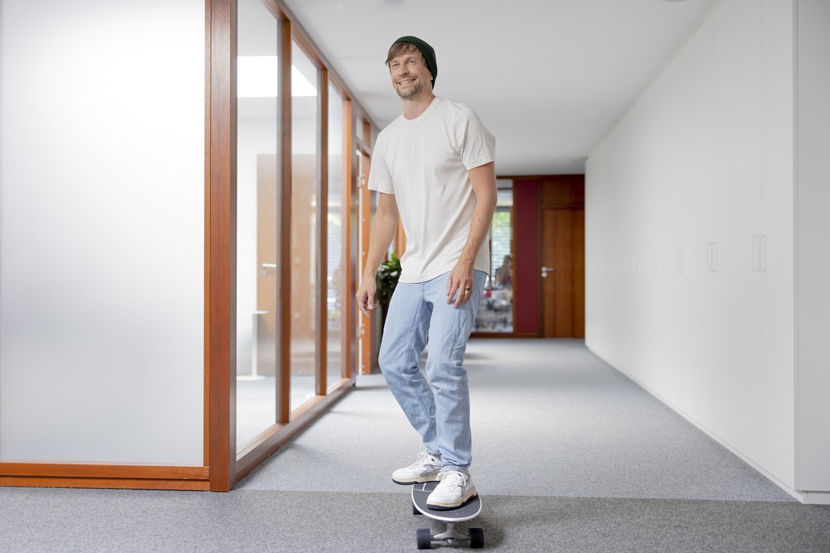 lockeres Portrait eines Geschäftsführers, der im Büro Skateboard fährt | Foto: Hanna Witte