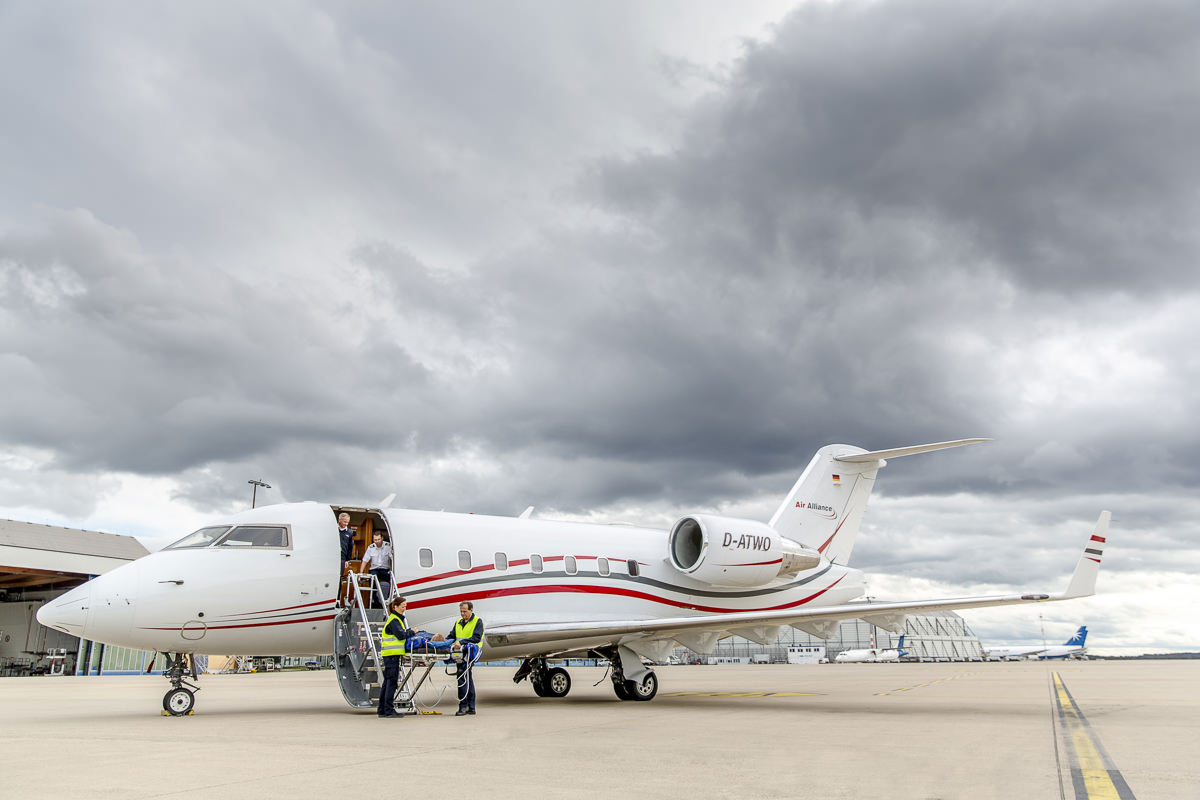 Die Crew eines Ambulanzflugzeugs von Air Alliance lädt einen Patienten aus
