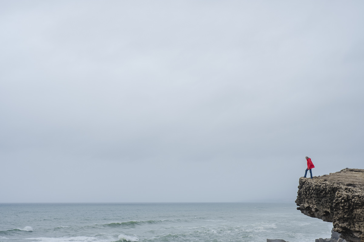 ein Mann auf einem Felsen an der Küste Portugals