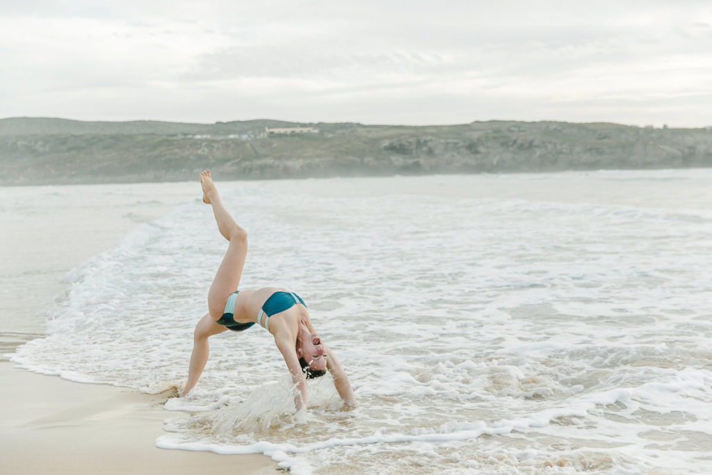 eine Frau bei einem Yoga Asana im Meer