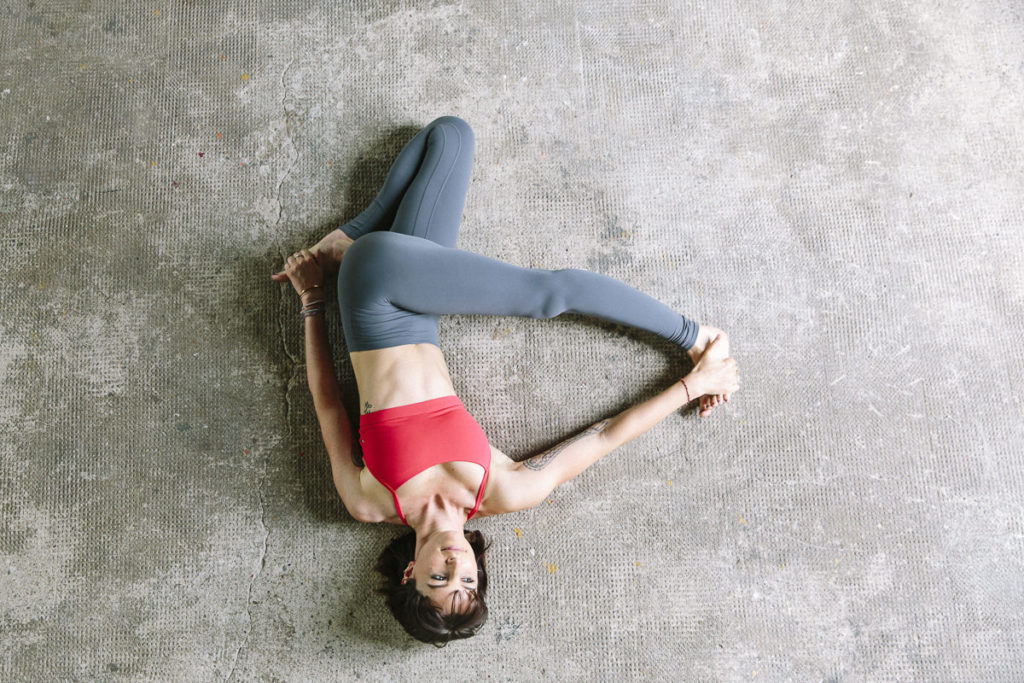 Wanda Badwal liegt auf dem Boden und zeigt ein Yoga Asana