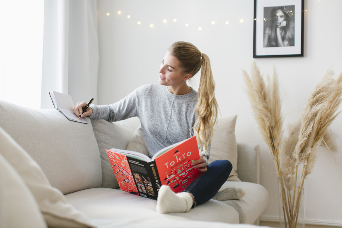 eine junge Frau liest auf der Couch ein Buch über Tokio als Teil der Social Media Content Fotografie für Eat Happy | Foto: Hanna Witte