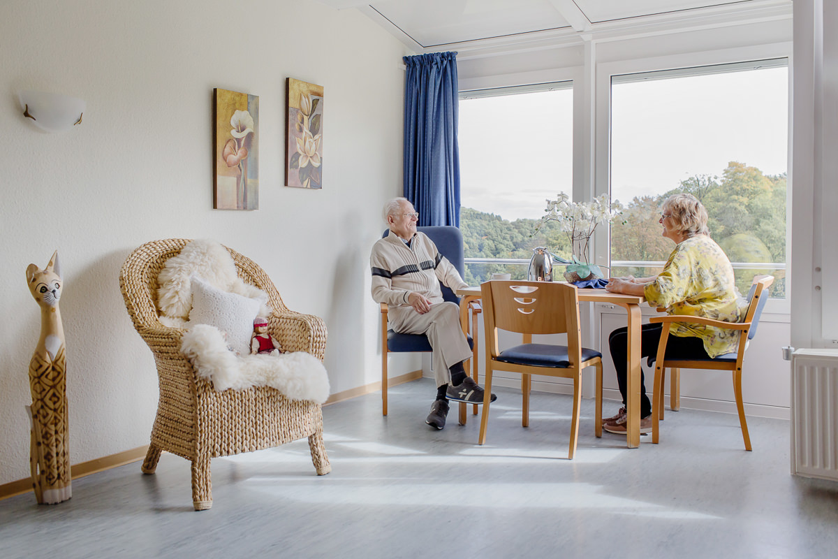 ein Seniorenheim Bewohner sitzt mit einer Betreuerin am Tisch und unterhält sich | Foto: Hanna Witte