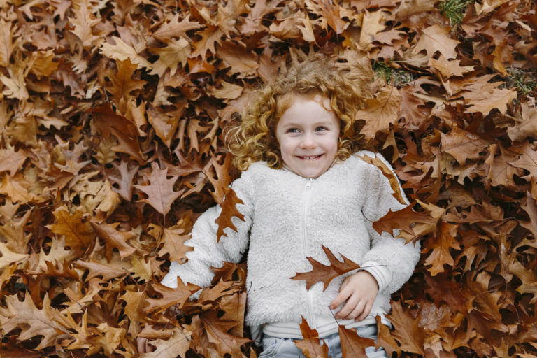 pflasterfüchse-website-fotos-001 ein Kind liegt zwischen Herbstblättern | Foto: Hanna Witte