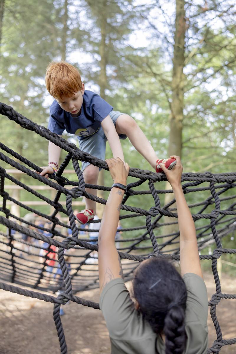 eine Arboretum Mitarbeiterin hilft einem Jungen ein Kletternetz zu überwinden | Foto: Hanna Witte
