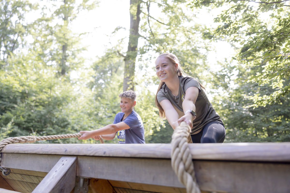 zwei Kinder überwinden mit einem Seil ein Kletterwandhindernis im Arboretum Naturparcours | Foto: Hanna Witte