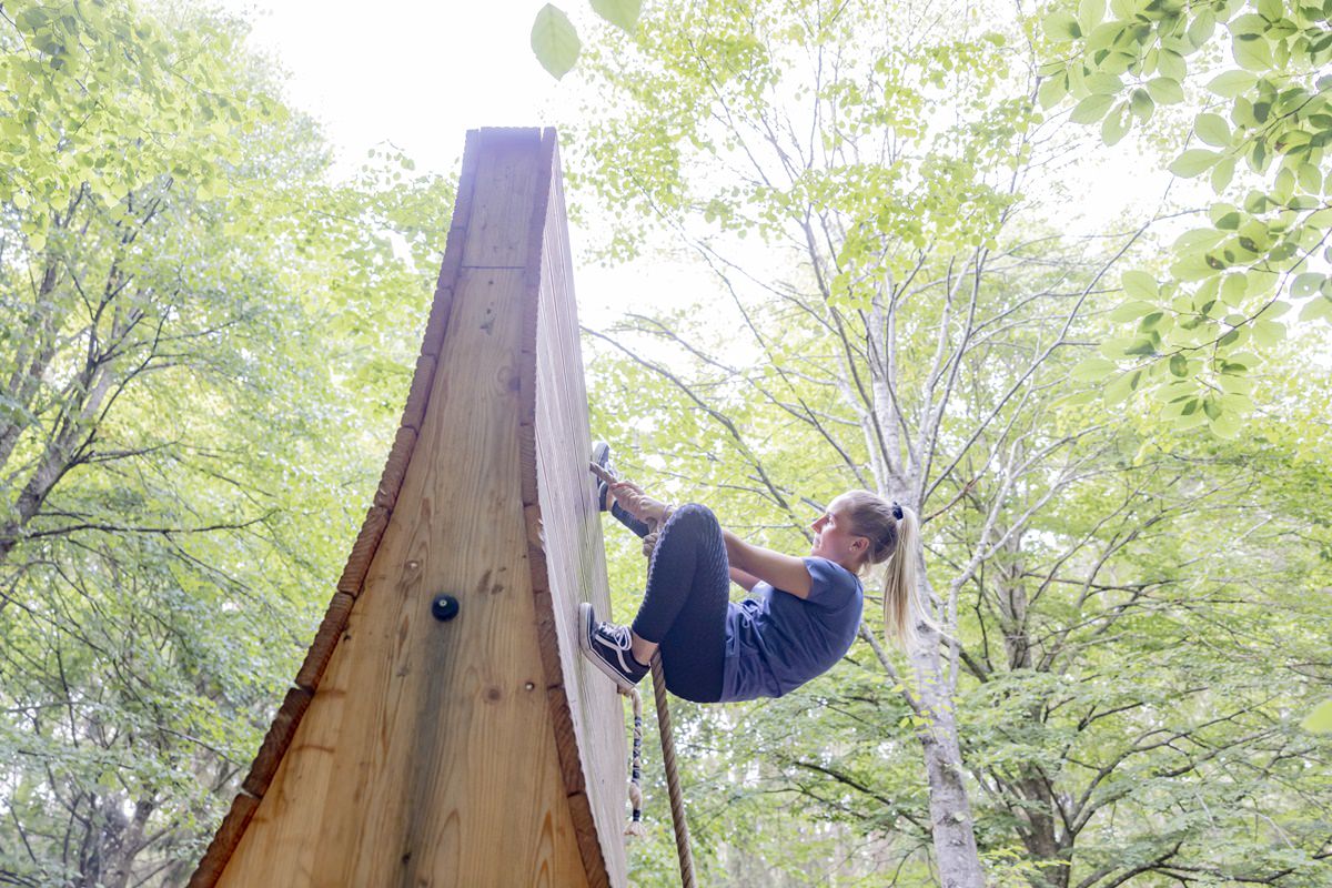 eine junge Frau klettert an einem Seil über ein Wandhindernis im Arboretum Naturparcours | Foto: Hanna Witte