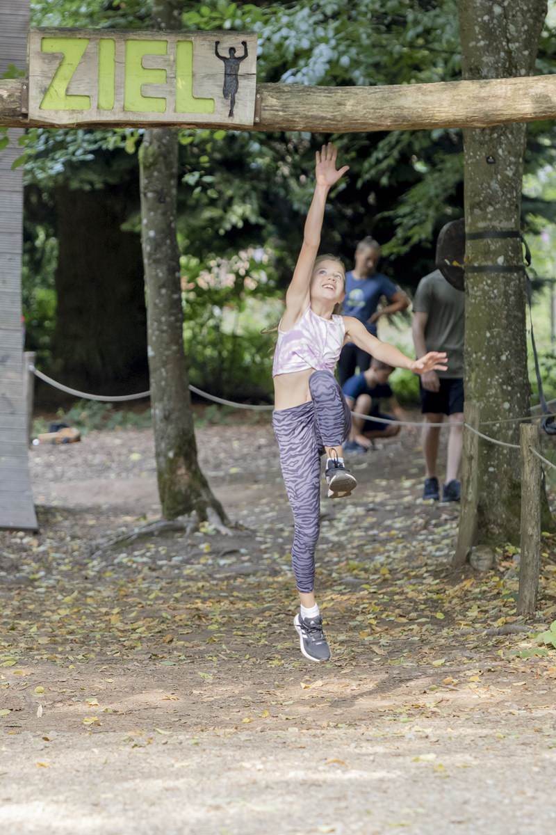 ein Mädchen springt an den Holzbogen des Ziels im Hindernisparcours Arboretum | Foto: Hanna Witte