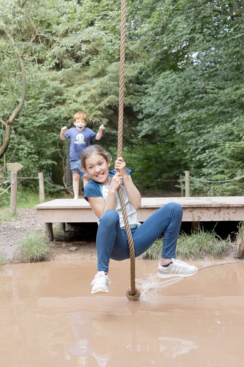 ein Mädchen schwingt an einem Seil über ein Wasserhindernis im Arboretum Naturparcours | Foto: Hanna Witte