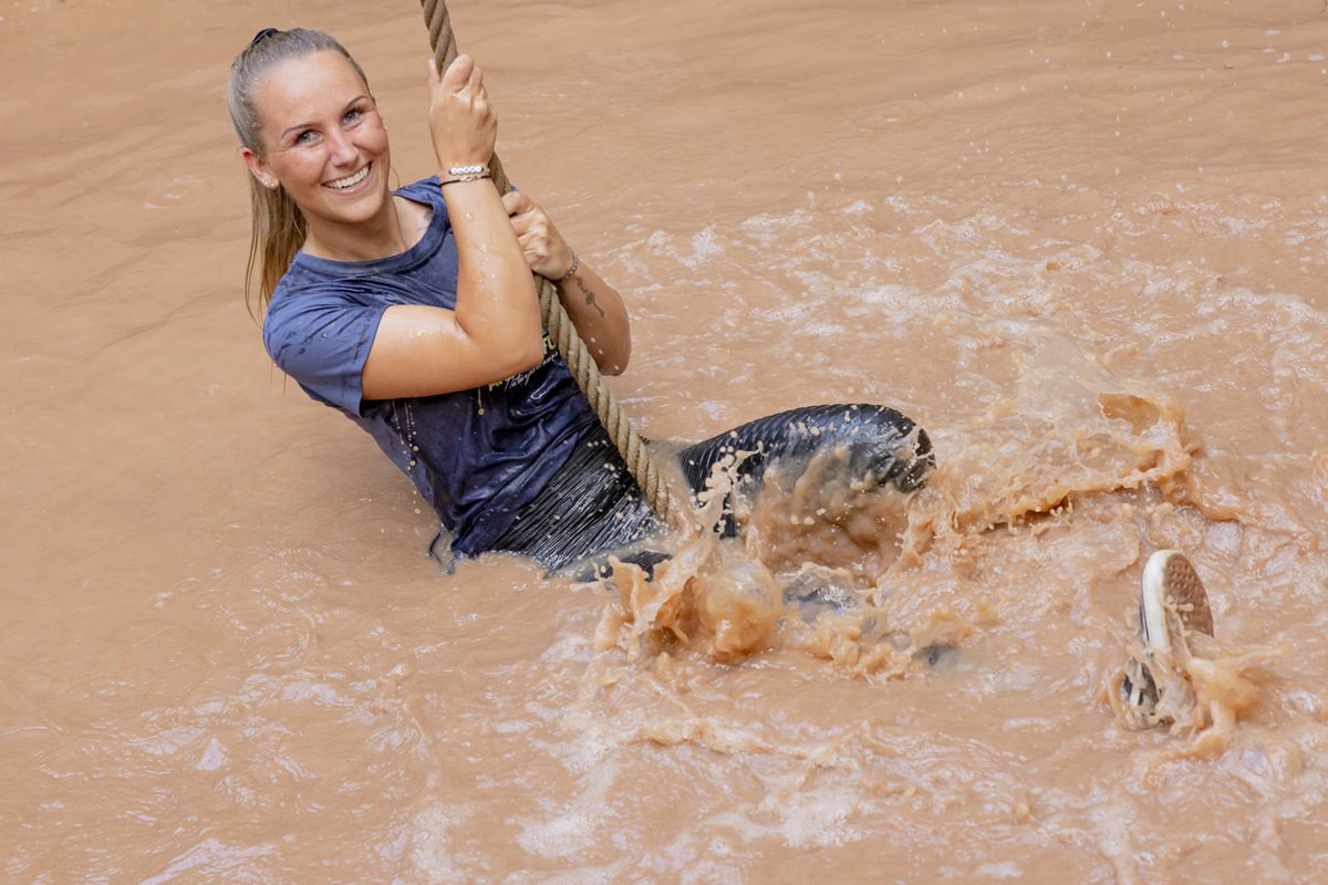 eine Arboretum Mitarbeiterin schwingt an einem Seil durch ein Wasserloch des Hindernisparcours | Foto: Hanna Witte