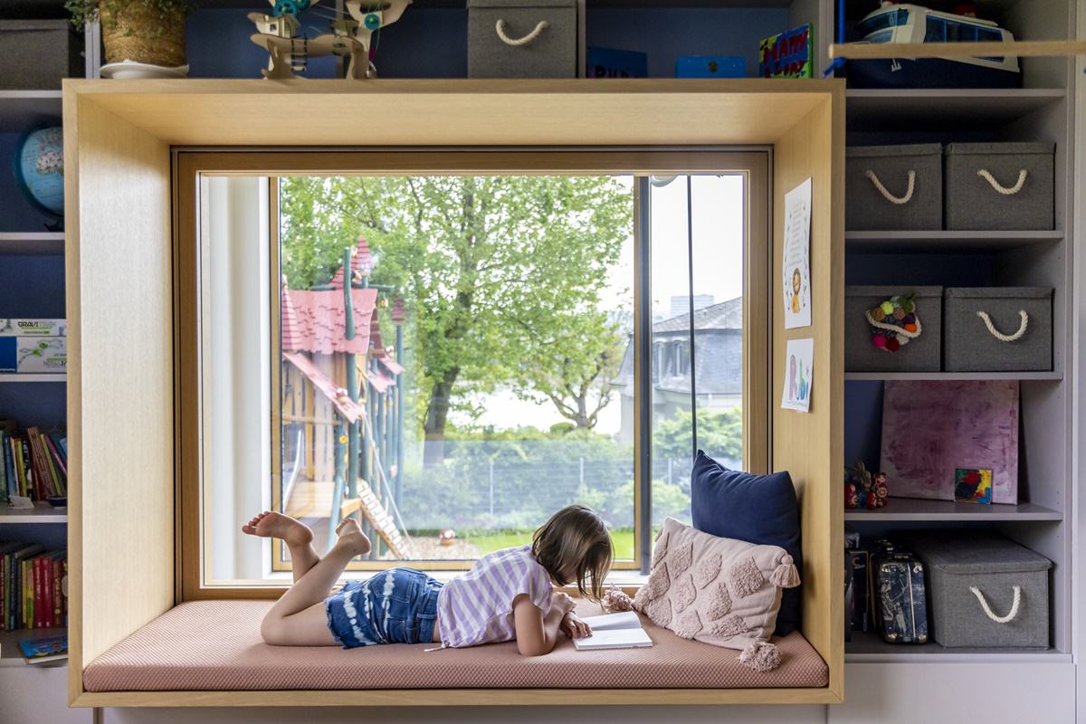 ein Kind liegt im Kinderzimmer auf einem Sitzfenster und liest | Foto: Hanna Witte