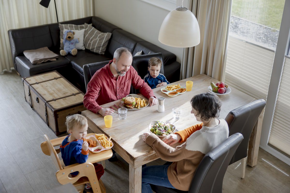 Eltern essen mit ihren Kindern im Ferienhaus eines Familienhotels zu Abend | Foto: Hanna Witte