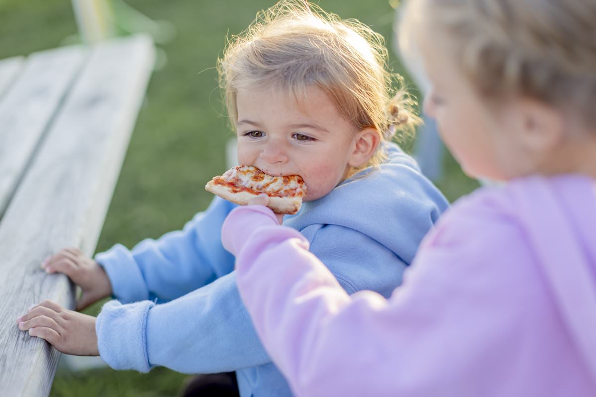 ein Kind füttert ein anderes Kind mit einem Stück Pizza | Foto: Hanna Witte