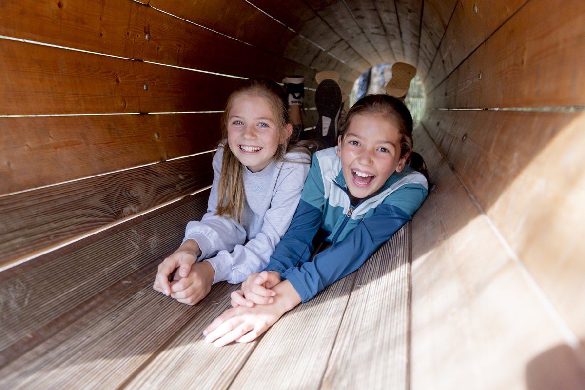 zwei Mädchen klettern durch eine Holzröhre im Arboretum Naturparcours | Foto: Hanna Witte