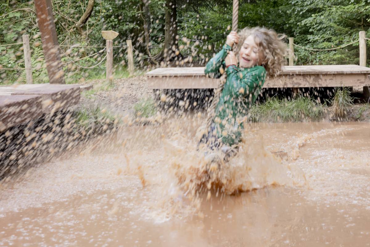 ein Kind schwingt mit einem Seil durch ein Wasserbecken im Arboretum Naturparcours | Foto: Hanna Witte