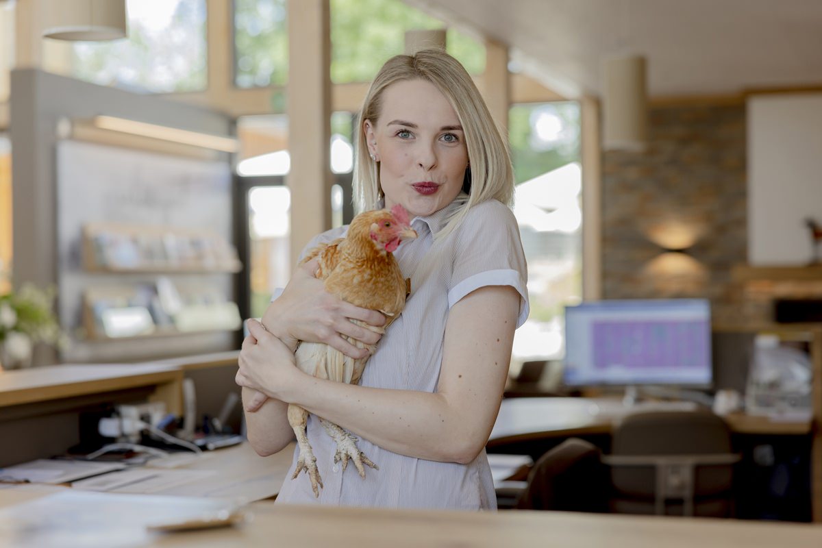 lustiges Mitarbeiterfoto von der Rezeptionistin eines Ferienhofs, die ein Huhn im Arm hält | Foto: Hanna Witte