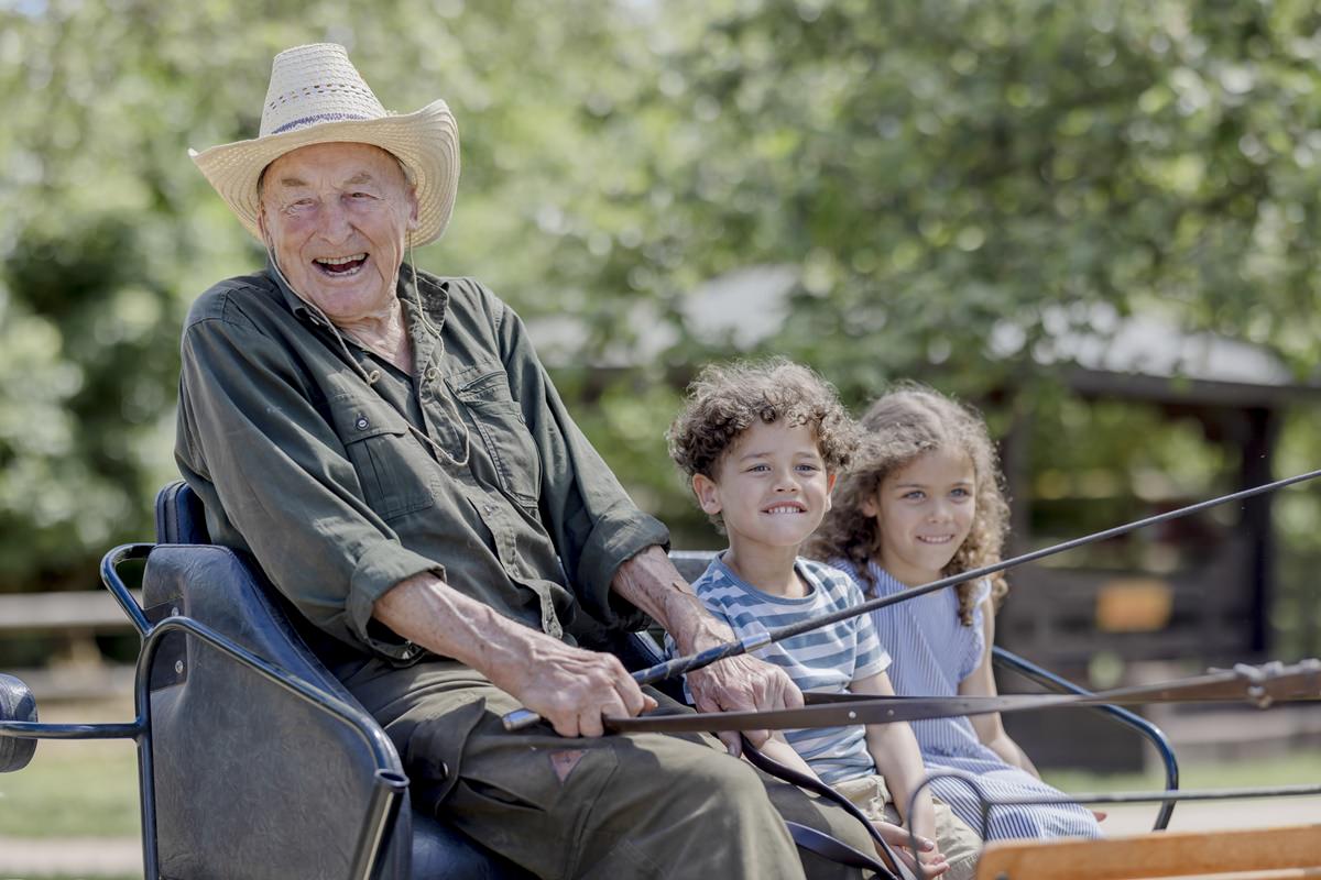 ein alter Kutscher fährt zwei Kinder mit der Kutsche eines Ferienhofs | Foto: Hanna Witte