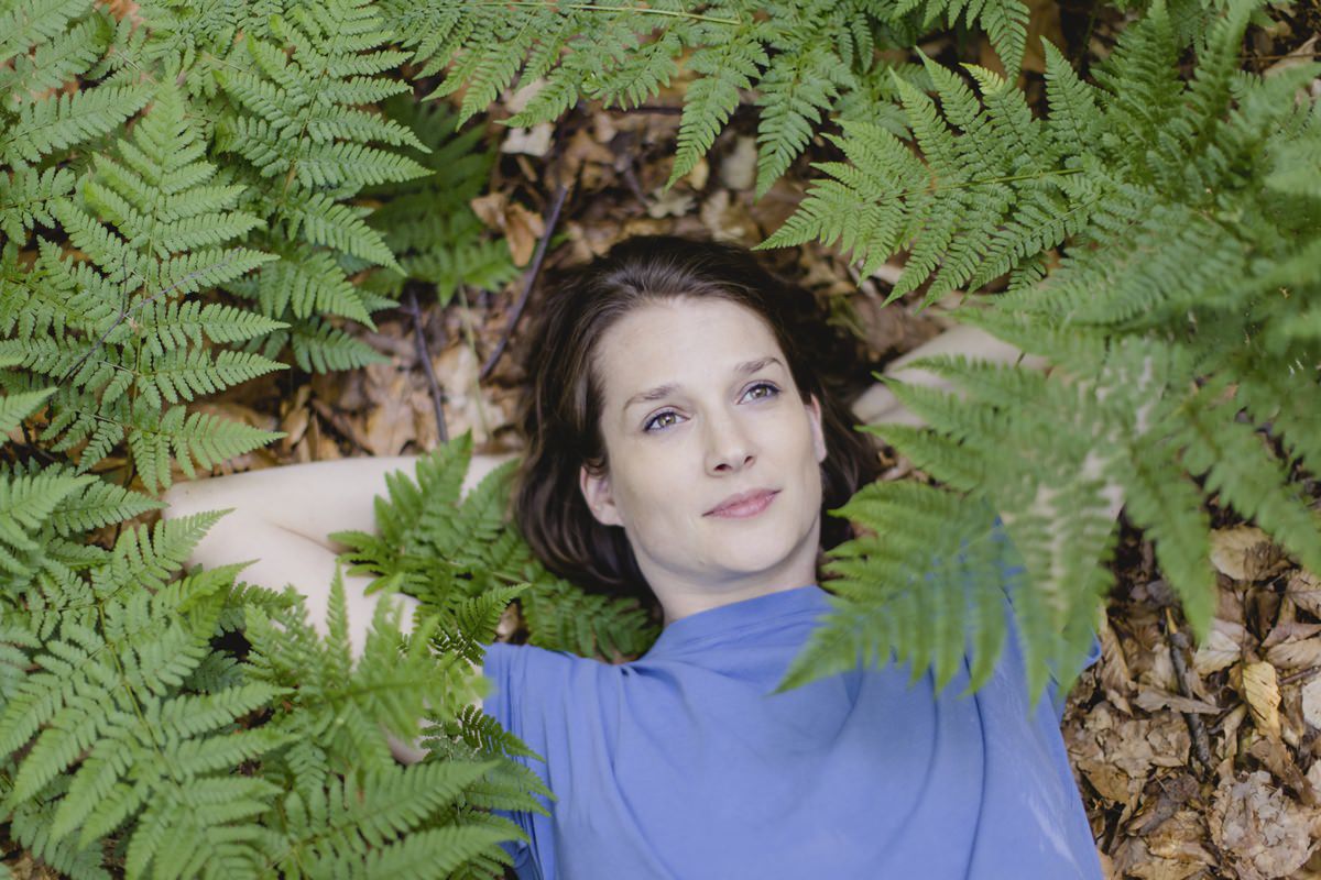 Portraitfoto von Architektin Marcella Hansch, die auf einem Wald Boden umgeben von Farn liegt | Foto: Hanna Witte