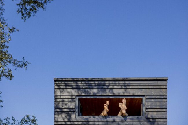 tiny-house-fotos-01 Gäste eines Kuckuck Tiny House halten ihre Füße aus einem Fenster | Foto: Hanna Witte