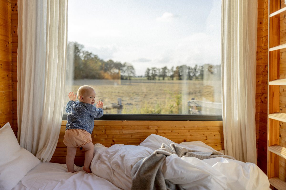 ein Baby steht an einem Fenster vom Kuckuck Tiny House | Foto: Hanna Witte