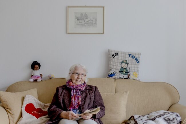 eine Demenz-WG Bewohnerin sitzt auf einem beigen Sofa | Foto: Hanna Witte