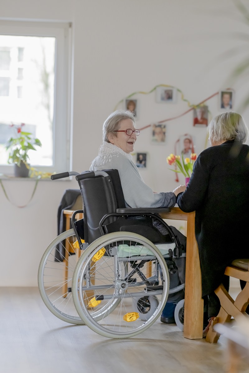 eine Demenz-WG Bewohnerin im Rollstuhl unterhält sich mit einer Betreuerin | Foto: Hanna Witte