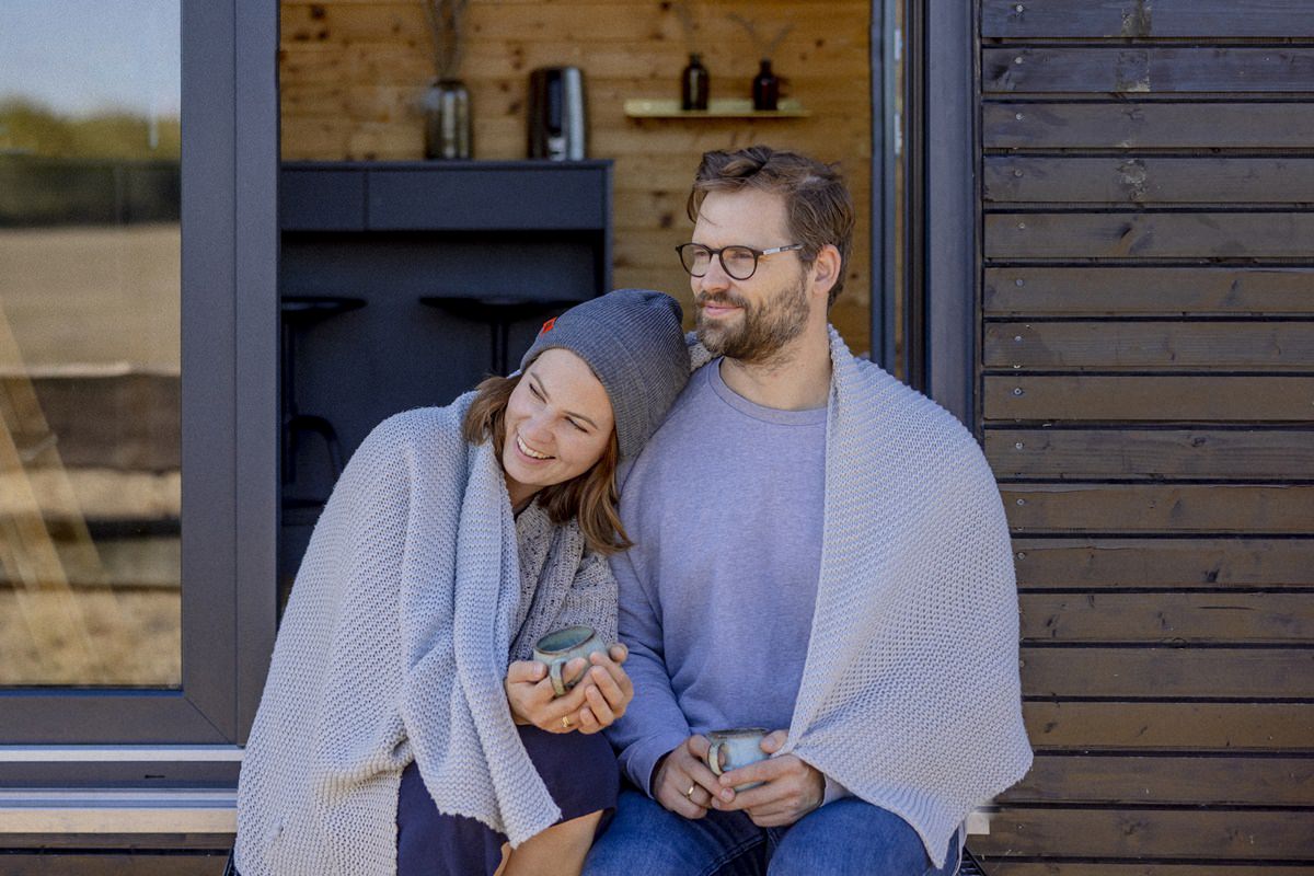 ein Pärchen sitzt vor der Tür zum Kuckuck Tiny House im Münsterland | Foto: Hanna Witte