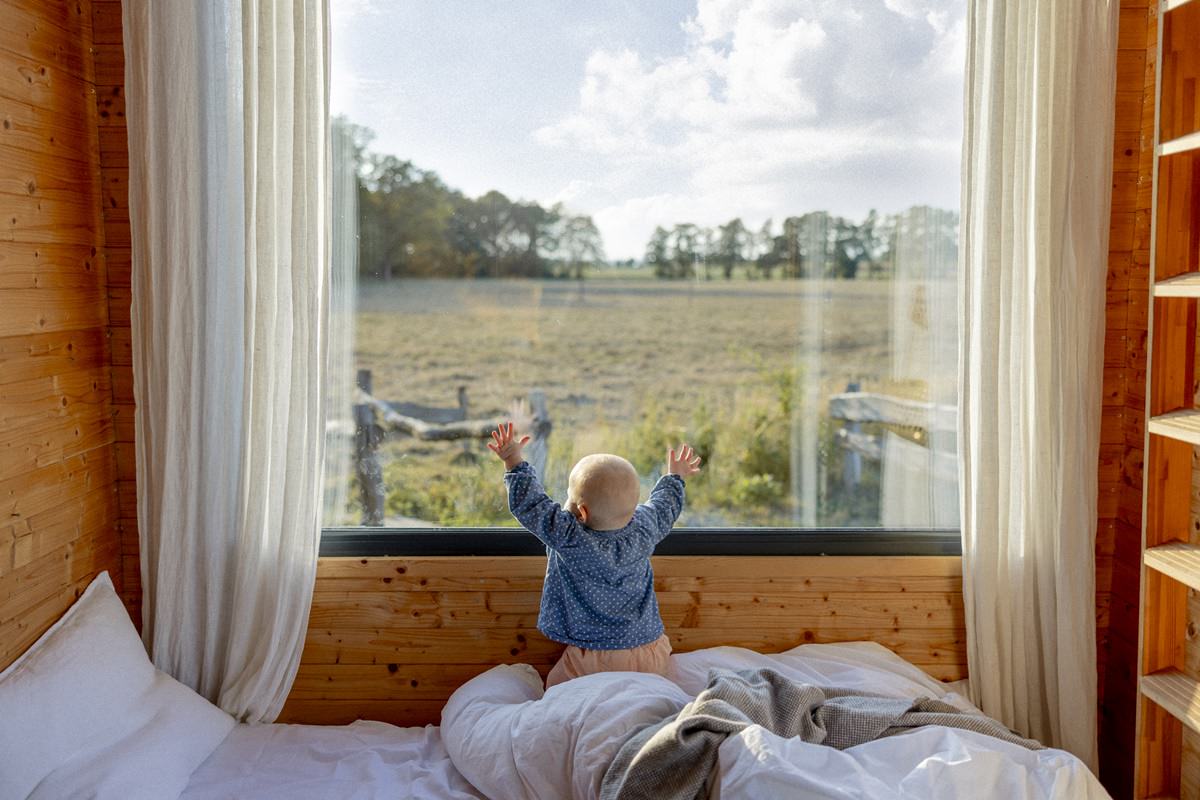 ein Kleinkind schaut aus dem Panorama Fenster eines Kuckuck Tiny House im Münsterland | Foto: Hanna Witte