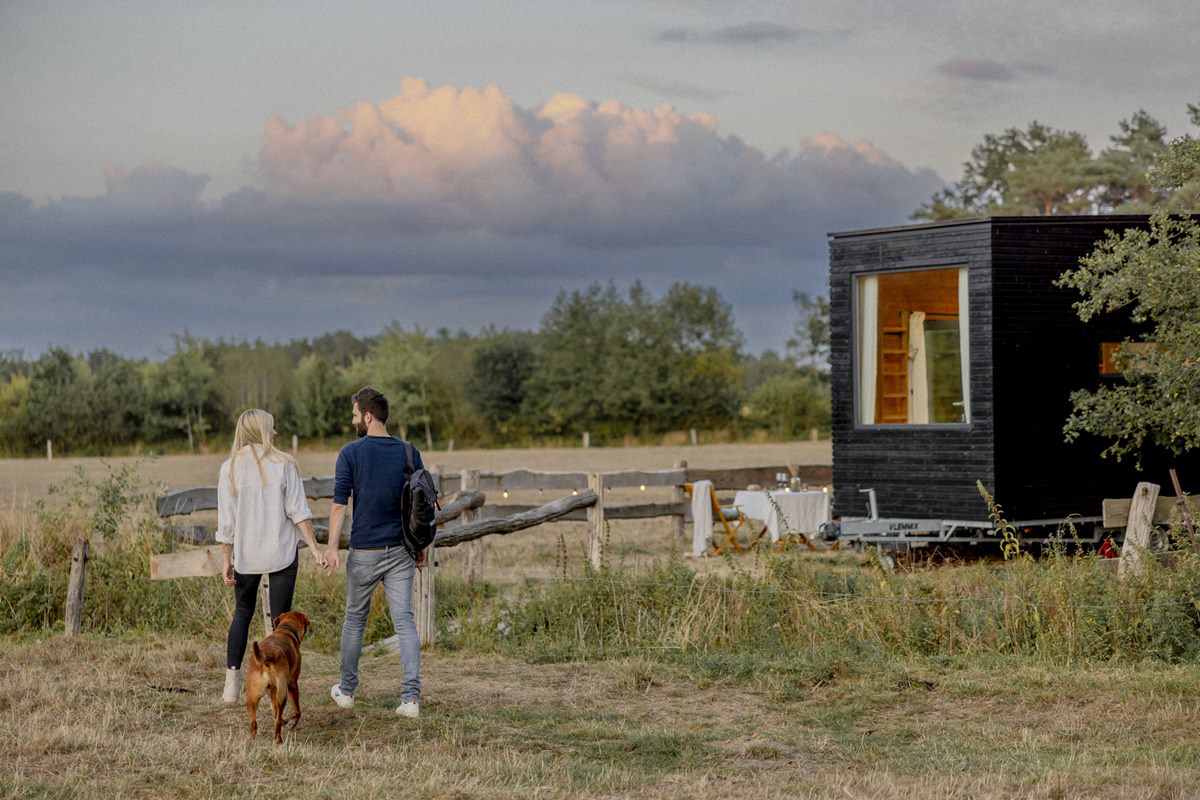 ein Pärchen samt Hund gehen vor dem Kuckuck Tiny House spazieren | Foto: Hanna Witte