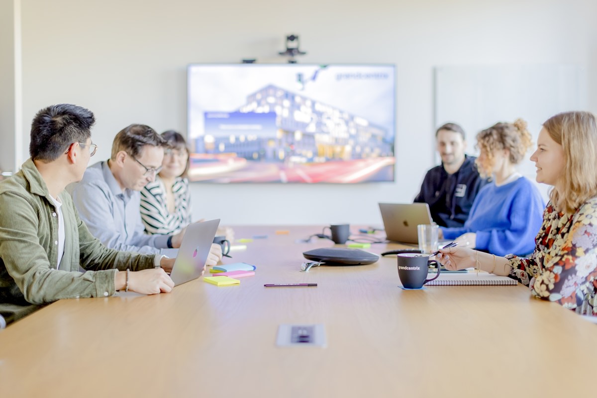 Mitarbeiter von grandcentrix sitzen bei einem Meeting an einem großen Konferenztisch | Foto: Hanna Witte