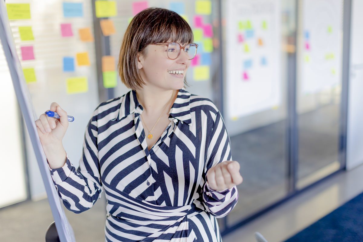 eine grandcentrix Mitarbeiterin erklärt einen Arbeitsschritt an einem Flipchart | Foto: Hanna Witte