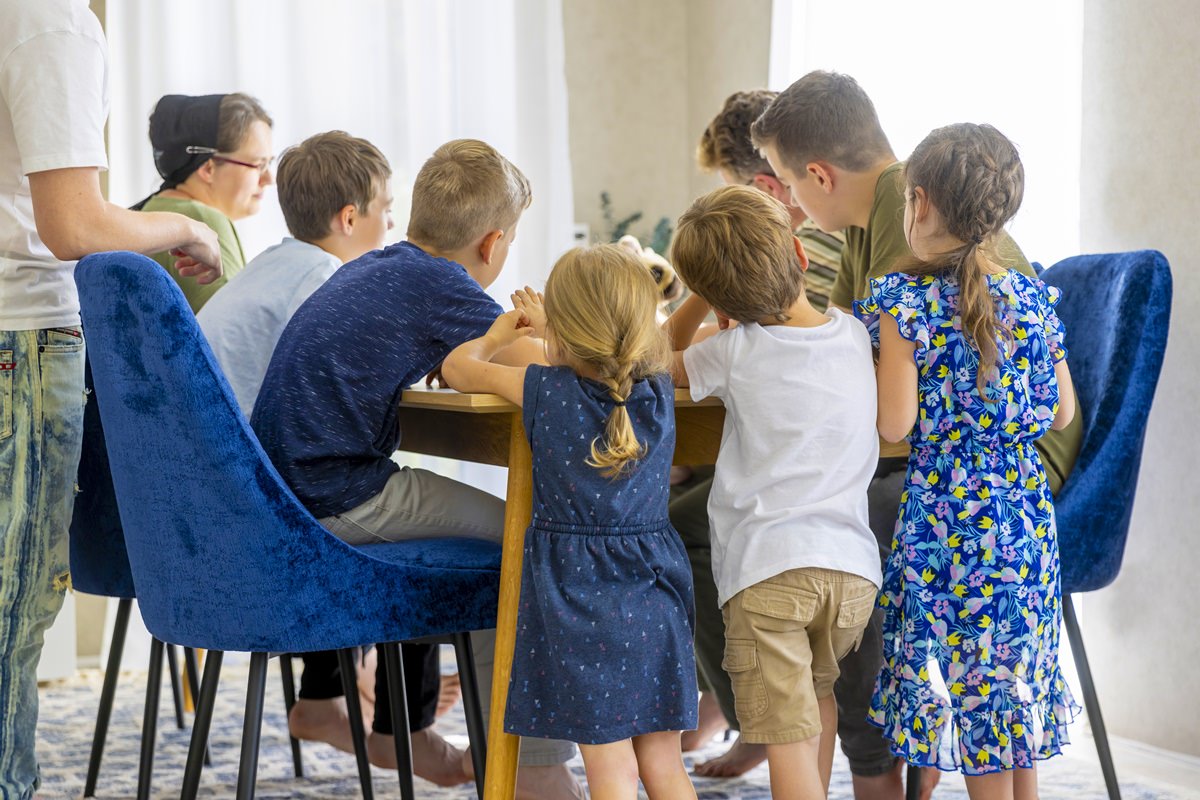 eine elfköpfige Familie beim gemeinsamen Spielen am Esstisch | Foto: Hanna Witte
