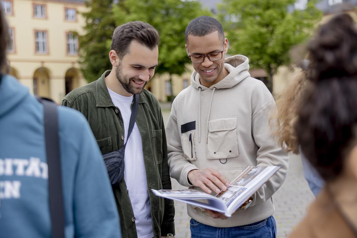 zwei Studenten der Uni Siegen schauen gemeinsam in ein Buch | Foto: Hanna Witte