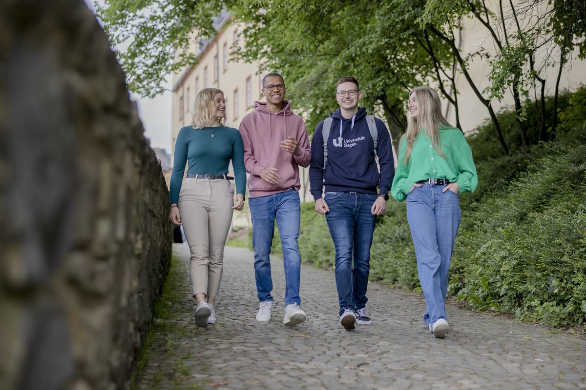 vier Studenten der Uni Siegen laufen gemeinsam über das Unigelände | Foto: Hanna Witte
