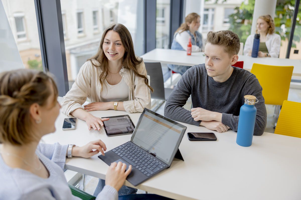 drei Studenten der Uni Siegen im Gespräch an einem Mensatisch | Foto: Hanna Witte