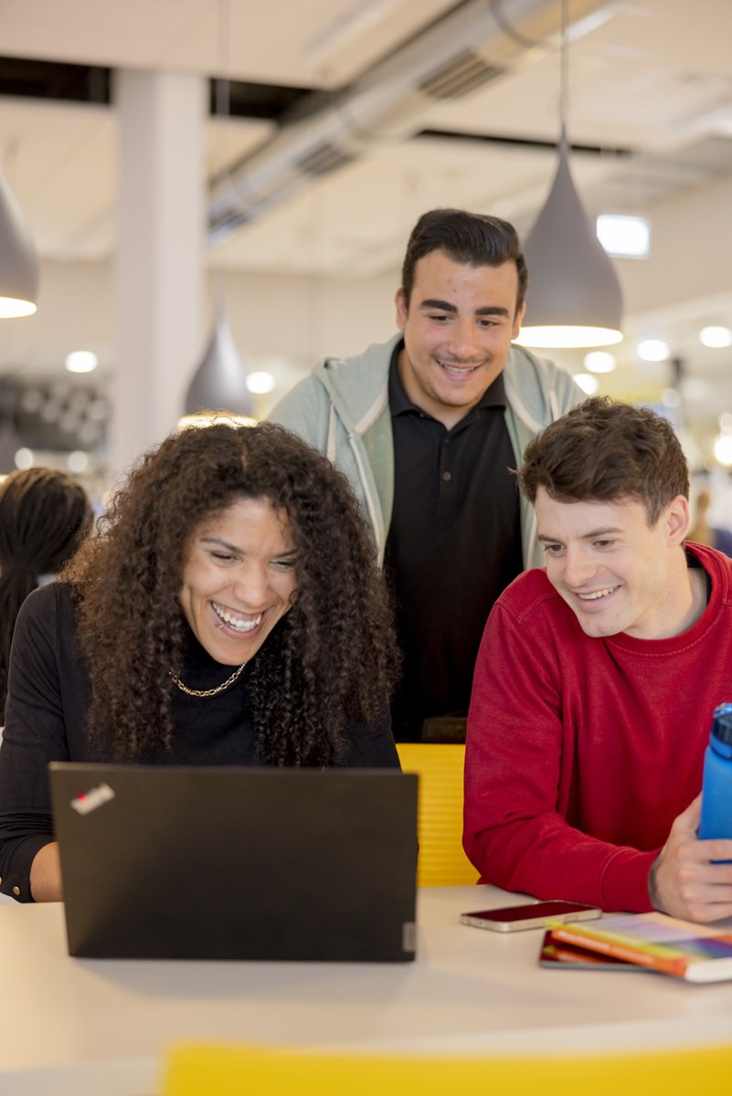 drei Studenten der Uni Siegen schauen in der Mensa auf einen Laptop | Foto: Hanna Witte