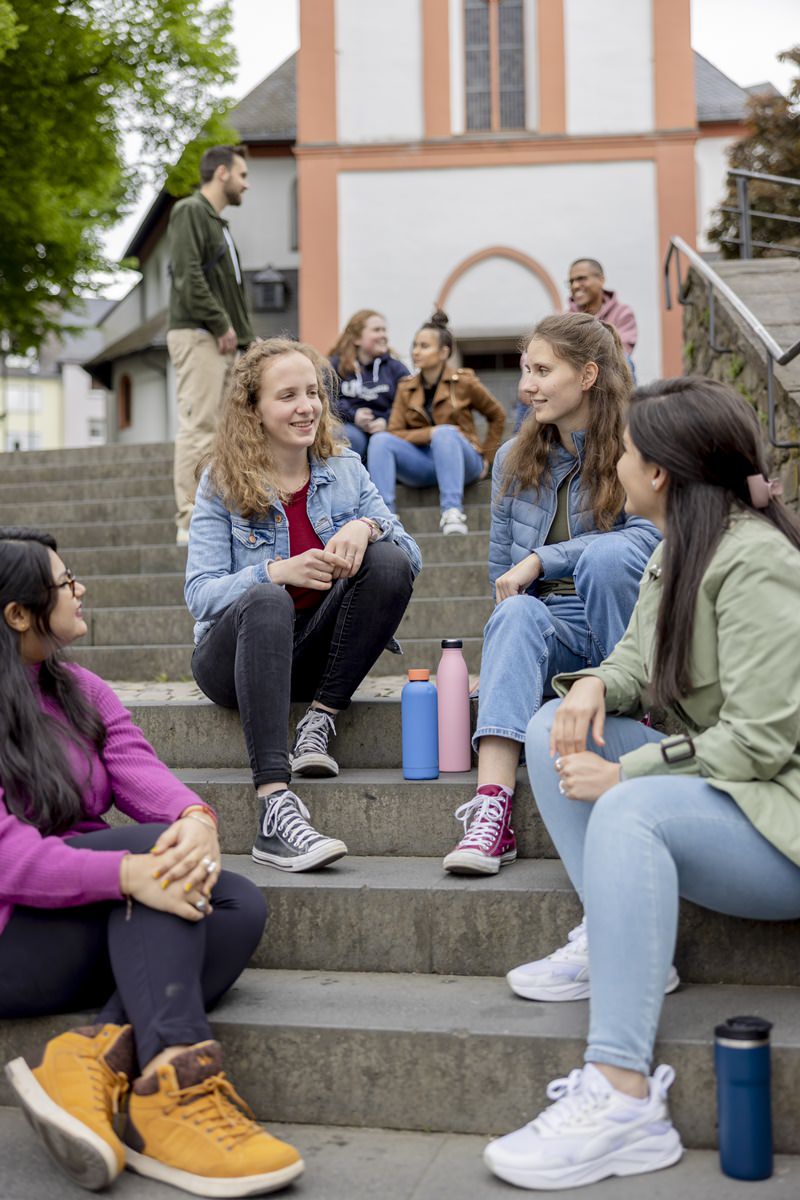 Studentinnen der Uni Siegen sitzen gemeinsam auf einer Treppe im Außenbereich | Foto: Hanna Witte