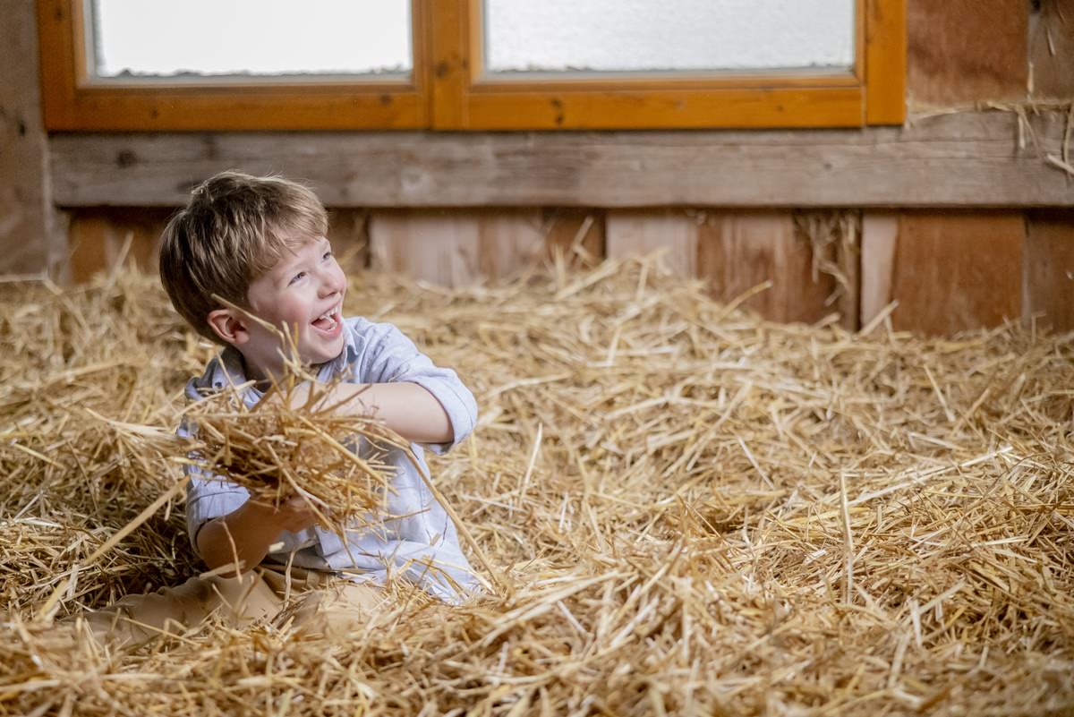 ein Junge spielt im Stroh des Stalls von Ferienhof Hardthöhe | Foto: Hanna Witte