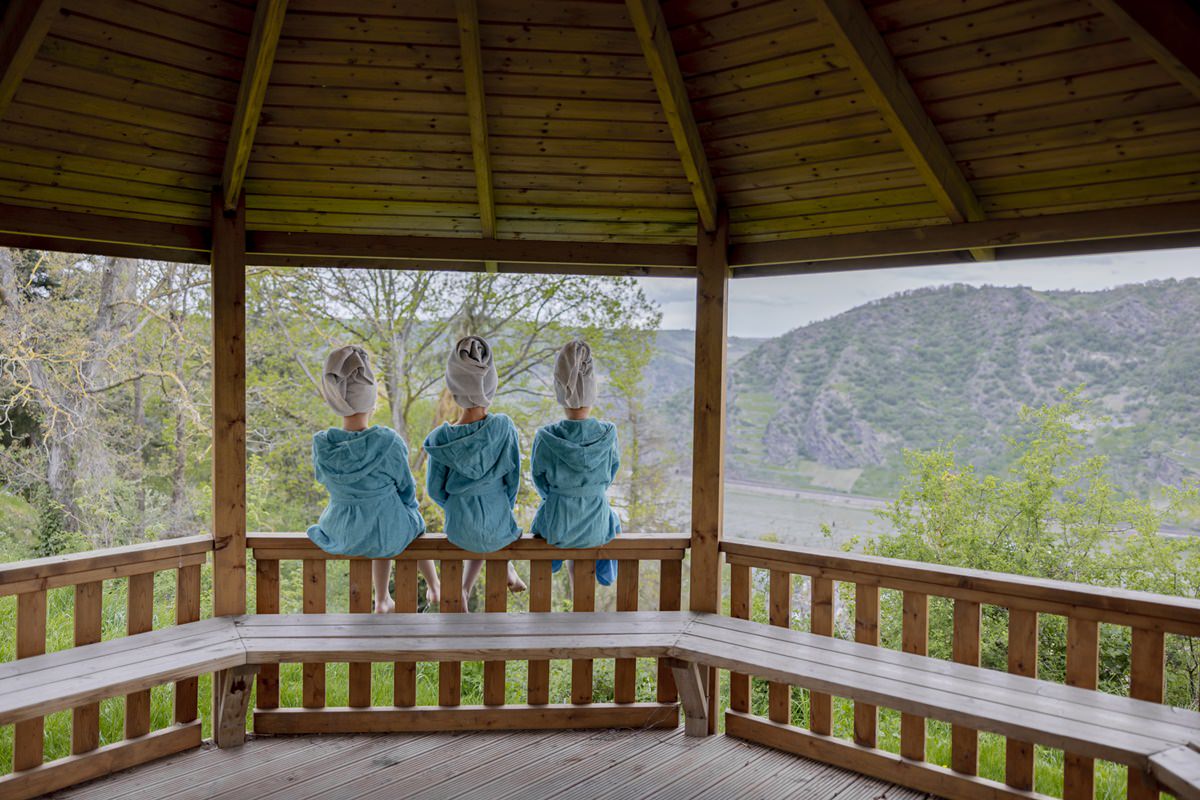 drei Mädchen in Bademänteln sitzen auf dem Geländer eines Holzpavillons im Außenbereich von Ferienhof Hardthöhe | Foto: Hanna Witte